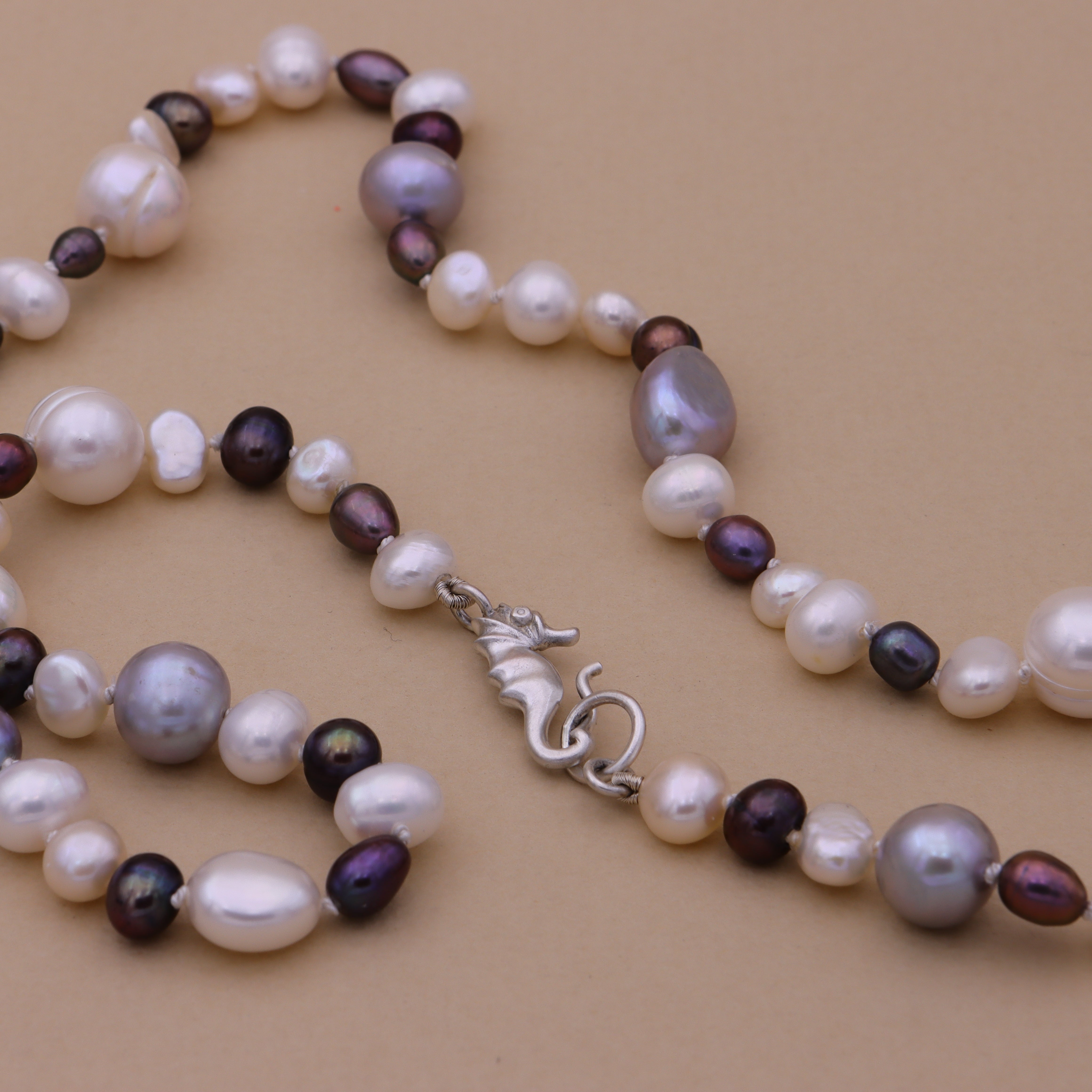 Ferskvandsperlekæde i hvis og blå med søhestlås i 925 sølv
